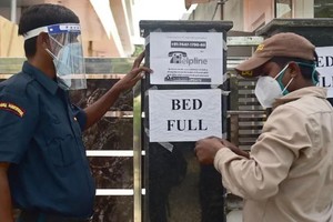 Nhân viên an ninh tại một bệnh viện tư nhân ở thành phố Allahabad, Ấn Độ thông báo hôm 22/4 tới người dân rằng bệnh viện này đã hết giường. Ảnh: AFP