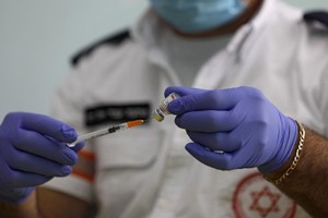 Nhân viên y tế Israel chuẩn bị mũi tiêm vaccine COVID-19 cho một học sinh tại làng Druze trên Cao nguyên Golan vào ngày 12/12. Ảnh: AFP