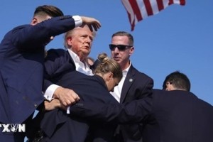 Cựu Tổng thống Donald Trump được mật vụ Mỹ hộ tống rời khỏi bục diễn thuyết trong cuộc vận động tranh cử ở thành phố Butler, bang Pennsylvania sau khi xảy ra vụ nổ súng, ngày 13/7. (Ảnh: THX/TTXVN)