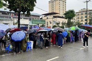 Người dân "đội mưa" xếp hàng nộp hồ sơ mua nhà ở xã hội.