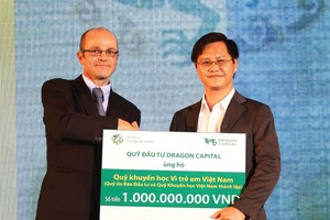 Ông Nguyễn Văn Hồng, Phó tổng Biên tập  Báo Đầu tư (bên phải), thay mặt Ban Biên tập Báo Đầu tư nhận món quà của Dragon Capital tặng cho Quỹ Học bổng Vì trẻ em Việt Nam do Báo Đầu tư sáng lập