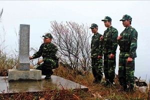 Các chiến sĩ biên phòng đứng trước cột mốc thiêng liêng của Tổ quốc trong một buổi tuần tra giáp Tết 