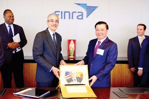 Bộ trưởng Đinh Tiến Dũng tặng quà cho Tổ chức Finra, Tổ chức giữ gìn sự liêm chính trên thị trường chứng khoán Mỹ, trong chuyến xúc tiến đầu tư tại New York, tháng 7/2015 