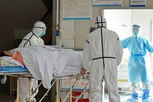 Các bác sĩ chuyển bệnh nhân nhiễm nCoV vào khu vực cách ly ở bệnh viện thành phố Phụ Dương, tỉnh An Huy hôm 1/2. Ảnh: AP.