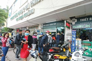 Người dân xếp hàng trước cửa nhà thuốc để chờ mua khẩu trang y tế, dung dịch sát khuẩn... Ảnh: Đức Thanh