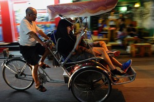 Du khách quốc tế ngồi xích lô tham quan phố cổ Hà Nội. (Ảnh: AFP)