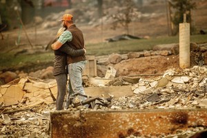 Cặp vợ chồng ôm nhau giữa ngôi nhà đã bị ngọn lửa thiêu hủy hoàn toàn tại thị trấn Paradise hôm 12/11. Ảnh: AP.