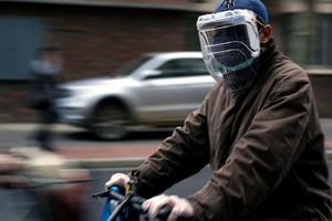 Một người dân đeo khẩu trang và mặt nạ tự chế từ chai nhựa trên đường phố Thượng Hải, Trung Quốc hôm 22/3. Ảnh: Reuters.