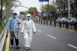 Dân Vũ Hán mặc đồ bảo hộ đi trên phố ngày 31/3. Ảnh: AFP.
