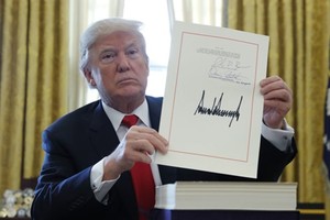 Tổng thống Mỹ Donald Trump cầm bản cải cách thuế với chữ ký của ông tại Phòng Bầu dục, Nhà Trắng, ngày 22/12 (Ảnh: VnEpress/Reuters)