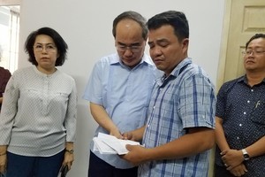 Bí thư Thành ủy Nguyễn Thiện Nhân hỗ trợ số tiền 60 triệu cho gia đình nạn nhân tử nạn trong vụ cháy chung cư Carina. Ảnh: Phước Tuần. 