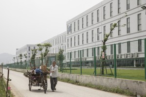 Một người đàn ông đang kéo một chiếc xe kéo phía trước nhà máy được điều hành bởi Tập đoàn Công nghệ Quang học Sunny. (Nguồn: Qilai Shen/Bloomberg).