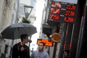 Người dân đi qua một quầy đổi tiền ở thủ đô Buenos Aires. Ảnh: AP.