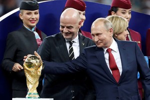 Tổng thống Nga Putin (phải) chạm vào cúp vàng World Cup sau trận chung kết hôm qua. Ảnh: Reuters. 