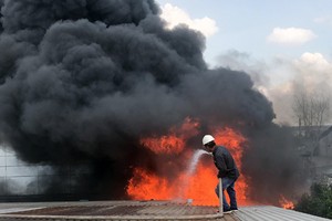 Công nhân cố dập lửa trong đám cháy. Ảnh: Tin Tin.