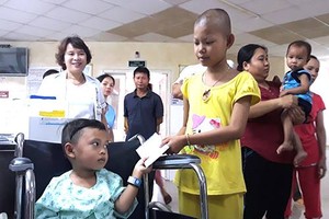 Em Tiến (ngồi xe lăn) trao quà hỗ trợ cho các bệnh nhi nghèo. Ảnh: X.D.