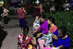 Người nhà bế theo bệnh nhi ngồi chờ dưới sân tòa nhà. Ảnh: Hương Giang.