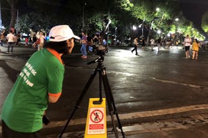 Nhân viên công ty môi trường ghi hình người xả rác bừa bãi ở phố đi bộ Hồ Gươm. Ảnh: N.H.