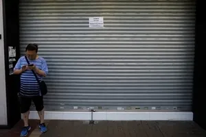 Một người qua đường đứng trước cửa tiệm dán thông báo đóng cửa vì biểu tình ở Hong Kong hôm 5/8. Ảnh: Reuters.