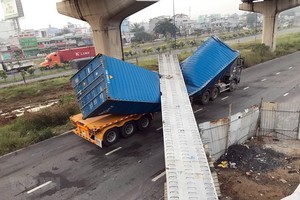 Xe container bị dầm bêtông đè lên dập móp. (Ảnh: TTXVN phát)