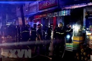 Cảnh sát phòng cháy chữa cháy phá cửa để cứu hộ. (Ảnh: TTXVN)