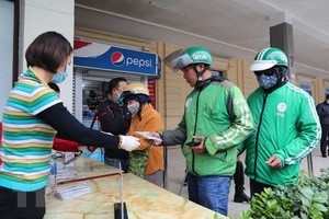 Phát miễn phí khẩu trang y tế cho lái xe Grab. (Ảnh: Thành Đạt/TTXVN).