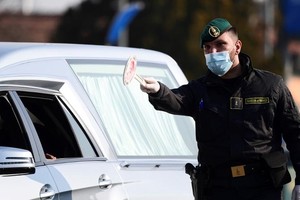 Nhân viên an ninh điều khiển giao thông tại một trạm kiểm soát ở thị trấn Zorlesco, vùng Lombardy, Italy hôm 24/2. Ảnh: AFP.