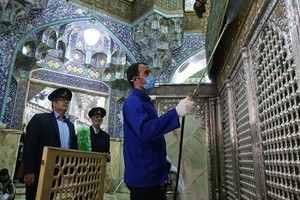 Nhân viên vệ sinh khử trùng đền thờ Masumeh ở thành phố Qom, Iran hôm 25/2. Ảnh: AFP.