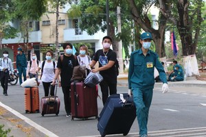 Lực lượng dân quân tự vệ Thành phố hỗ trợ người cách ly trở về nhà sau khi hoàn thành cách ly 14 ngày. (Ảnh: Thanh Vũ/TTXVN).