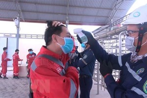 Tất cả các chuyên gia, lao động đều phải đo thân nhiệt cũng như rửa tay, sát khuẩn, khai báo y tế trước khi vào làm việc tại Khu kinh tế Nghi Sơn. (Ảnh: Khiếu Tư/TTXVN).