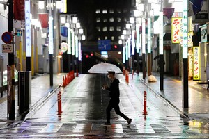 Nam thanh niên đi qua một đường phố Tokyo vắng vẻ hôm 16/4. Ảnh: Reuters.