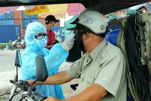 Nhân viên y tế đo thân nhiệt người ra vào thành phố Hồ Chí Minh tại chốt kiểm dịch. (Ảnh: Đinh Hằng/TTXVN).