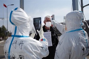 Nhân viên y tế Trung Quốc kiểm tra thân nhiệt ngăn chặn sự lây lan của dịch COVID-19 tại một trạm kiểm tra hải quan ở Suifenhe, tỉnh Hắc Long Giang, gần biên giới với Nga, ngày 1/5/2020. (Ảnh: AFP/TTXVN).