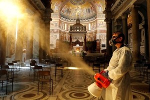 Người đàn ông khử trùng bên trong nhà thờ Santa Maria in Trastevere Basilica ở Rome, Italy, ngày 11/5. Ảnh: Reuters.