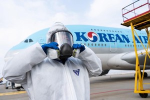 Nhân viên chuẩn bị phun thuốc khử trùng trên máy bay của Korean Air nhằm ngăn chặn sự lây lan của dịch COVID-19. (Ảnh: AFP/TTXVN).
