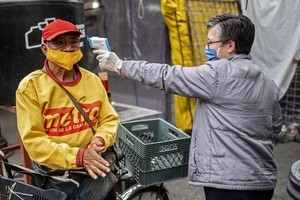 Một người đàn ông được đo thân nhiệt tại khu chợ ở thủ đô Mexico City của Mexico hôm 22/6. Ảnh: AFP.