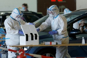 Nhân viên y tế lấy mẫu xét nghiệm nCoV trong nhà chứa máy bay của sân bay Guetersloh, Đức, ngày 27/6. Ảnh: Reuters.