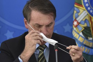 Tổng thống Jair Bolsonaro tháo khẩu trang trong cuộc họp báo. Ảnh: AP.