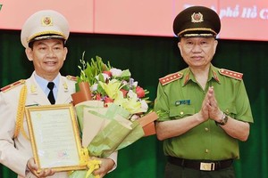 Đại tướng Tô Lâm thừa uỷ quyền của Chủ tịch nước trao quyết định và tặng hoa chúc mừng Thiếu tướng Đinh Thanh Nhàn.