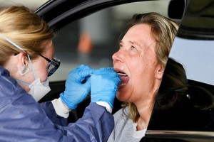 Nhân viên y tế lấy mẫu xét nghiệm nCoV tại một trạm kiểm tra trong xe ôtô ở Alkmaar, Hà Lan, hồi tháng 4. Ảnh: Reuters.