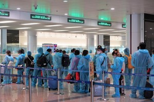 Hành khách trên chuyến bay quốc tế thương mại tới Việt Nam đầu tiên sau thời gian dài vì dịch COVID-19 làm thủ tục nhập cảnh tại sân bay Nội Bài. (Ảnh: CTV/Vietnam+).