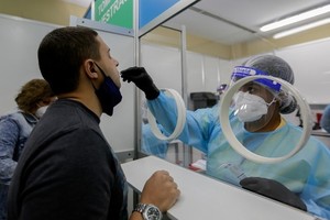 Nhân viên y tế lấy mẫu xét nghiệm Covid-19 cho một người đàn ông ở Sân bay Quốc tế Tocumen, Panama City, thủ đô của Panama hôm 12/10. Ảnh: AFP.