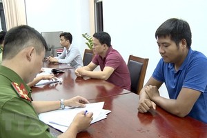 Lấy lời khai của nhóm đối tượng lừa đảo. (Ảnh: TTXVN phát).