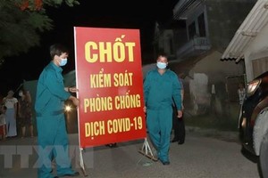 Lực lượng chức năng tiến hành tthu dọn vật dụng tại chốt cách ly tại thôn Tiền Phong, xã Tân Phong, huyện Bình Xuyên, Vĩnh Phúc. (Ảnh: Hoàng Hùng/TTXVN).