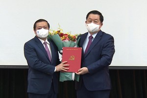 Ông Nguyễn Trọng Nghĩa trao quyết định và tặng hoa chúc mừng ông Lại Xuân Môn.