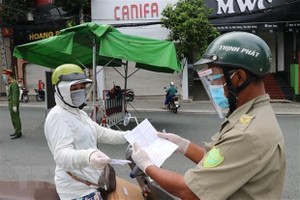 Một người phụ nữ đi chợ trình giấy có giấy tiêm đủ vaccine cho lực lượng kiểm tra trên đường Yersin, thành phố Thủ Dầu Một. (Ảnh: Chí Tưởng/TTXVN).