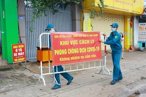 Lực lượng chức năng thực hiện dỡ bỏ phong tỏa cho 20 hộ dân tại khu phố 2, phường Xuân Thanh. (Ảnh: Lê Xuân/TTXVN).