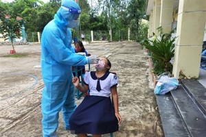 Lấy mẫu xét nghiệm COVID-19 cho học sinh, giáo viên tại Trường Tiểu học Thạnh An. (Ảnh: TTXVN phát).