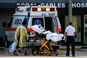 Nhân viên y tế chuyển bệnh nhân COVID-19 tới bệnh viện ở Coral Gables, gần Miami, Mỹ. (Ảnh: AFP/TTXVN).