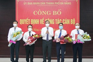 Ông Lê Trung Chinh (giữa), Chủ tịch UBND thành phố Đà Nẵng trao Quyết định và tặng hoa chúc mừng các cán bộ được điều động, bổ nhiệm vị trí công tác mới.